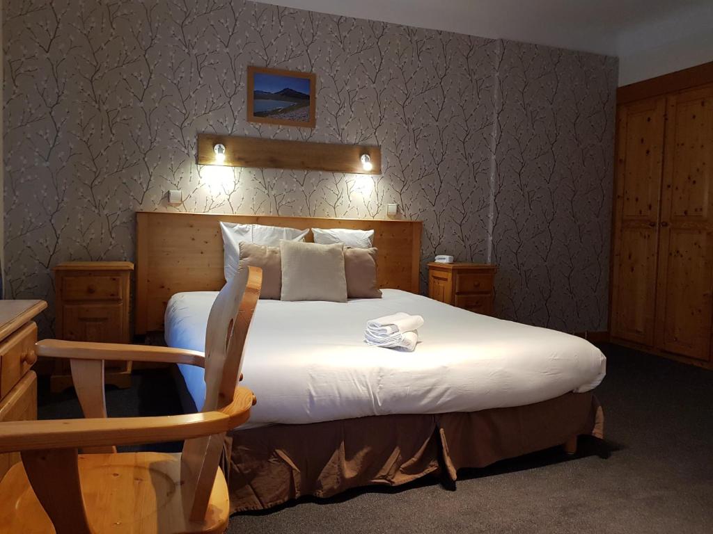 a bedroom with a large bed with a wooden headboard at Savoy Hotel & Restaurant in Saint-Michel-de-Maurienne