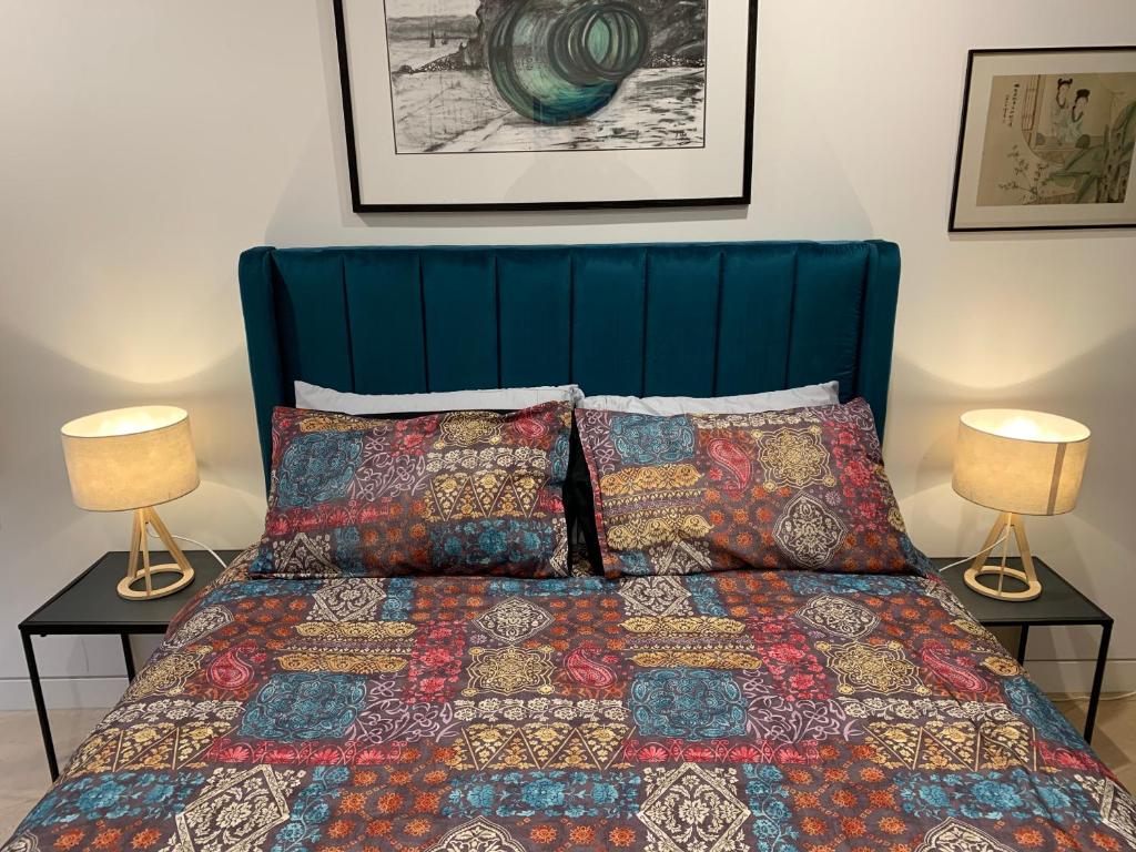 a bed with a blue head board with two lamps at Elwood by the Beach in Melbourne