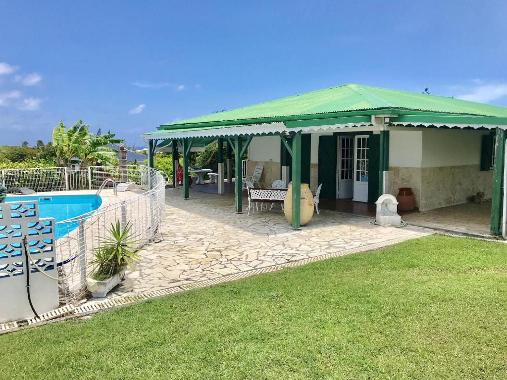 ein Haus mit einem grünen Dach und einem Pool in der Unterkunft Maison de 4 chambres a Saint Francois a 300 m de la plage avec vue sur la mer piscine privee et jardin clos in Saint-François