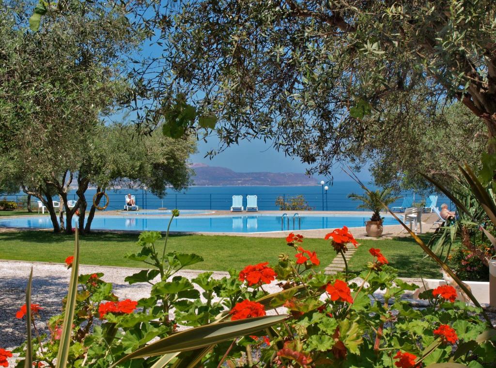 un giardino con fiori rossi e una piscina di Artemis Apartments a Kalyves