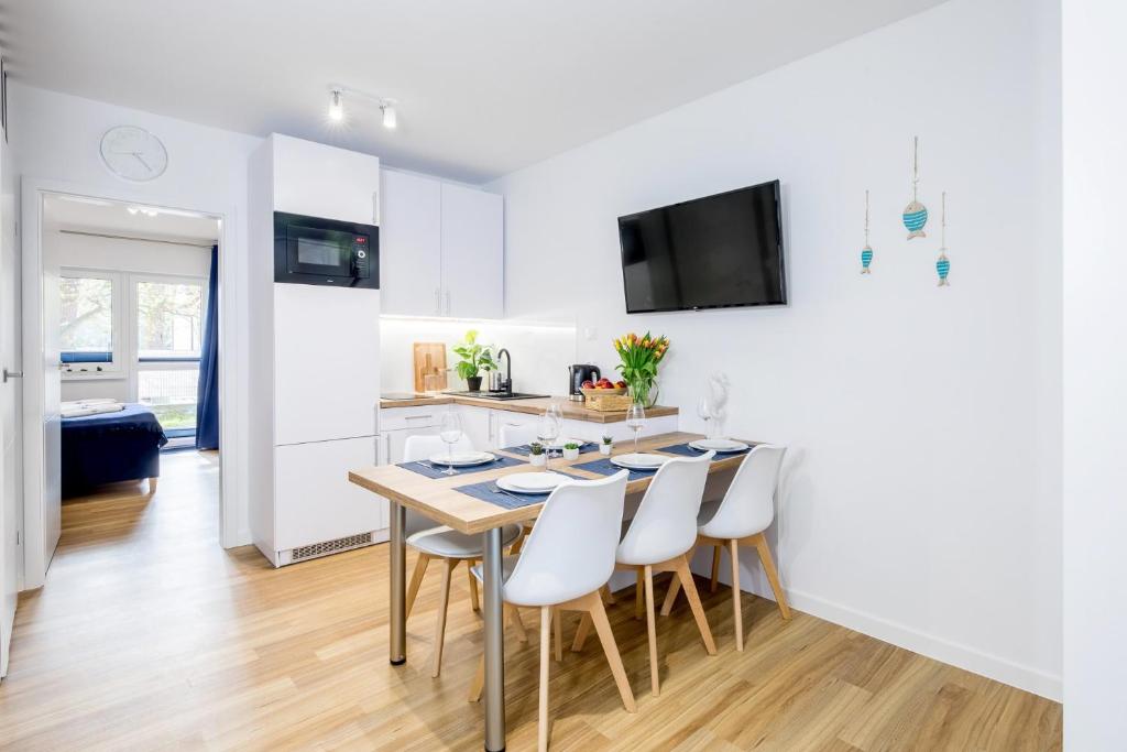 a kitchen and dining room with a table and chairs at Apartament 8B Blue Marine Poddąbie in Poddąbie