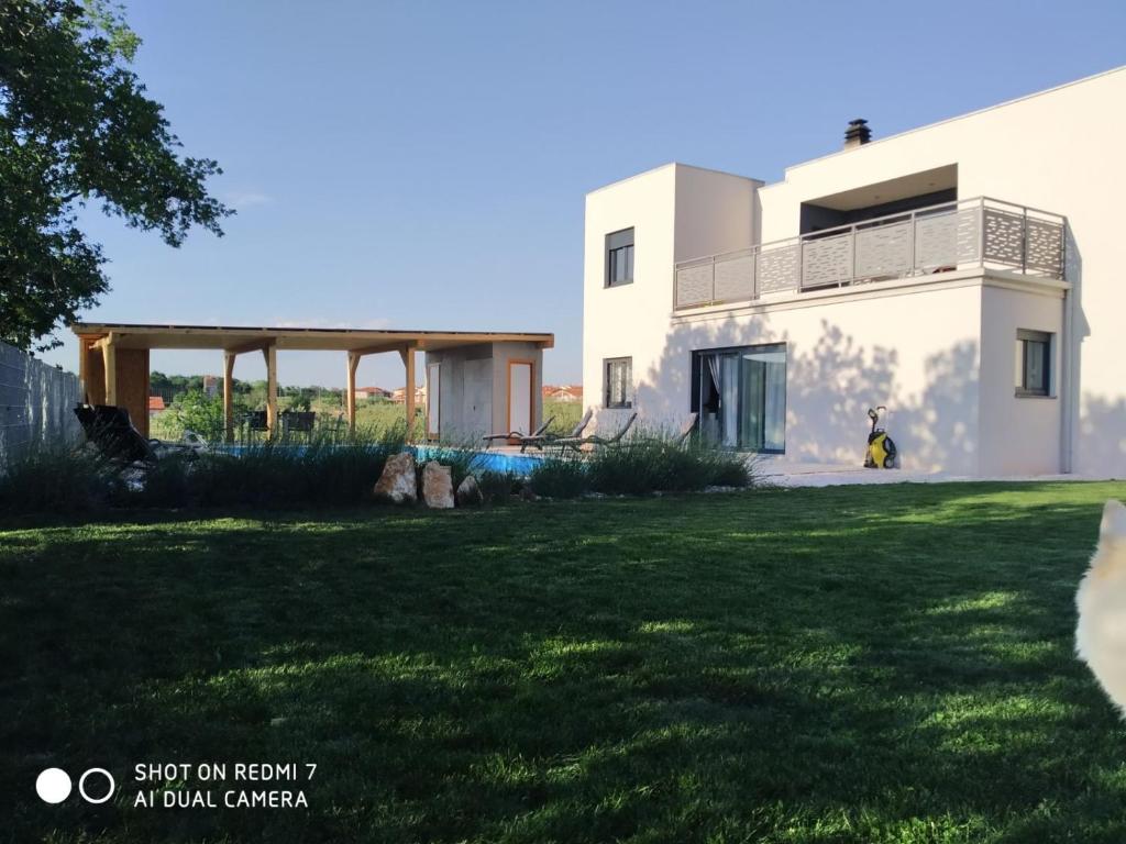 a white house with a yard in front of it at Enjoy Green, APP with swimming pool, garden, pets welcome in Novigrad Istria