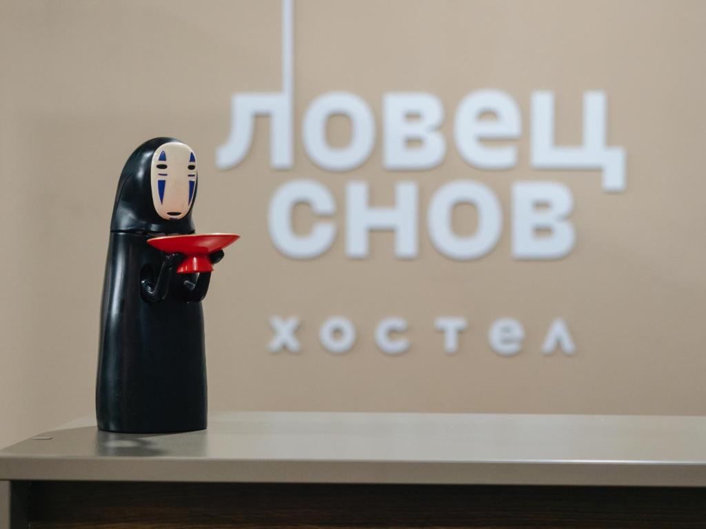 un pingüino de juguete sentado en una mesa frente a un cartel en Ловец Снов, en Chelyabinsk