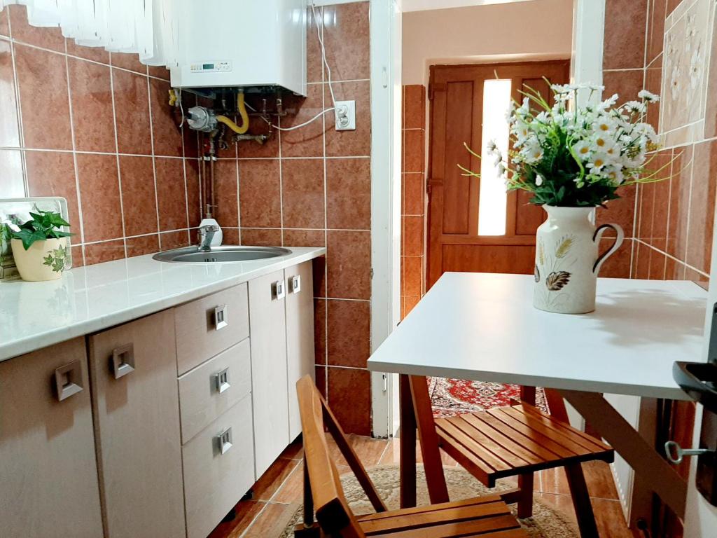 eine Küche mit einem Tisch und einer Vase aus Blumen in der Unterkunft Casa Hermann in Sighişoara