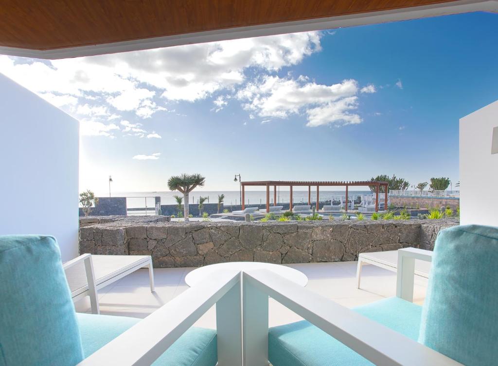 a balcony with chairs and a view of the ocean at Hotel Lava Beach in Puerto del Carmen