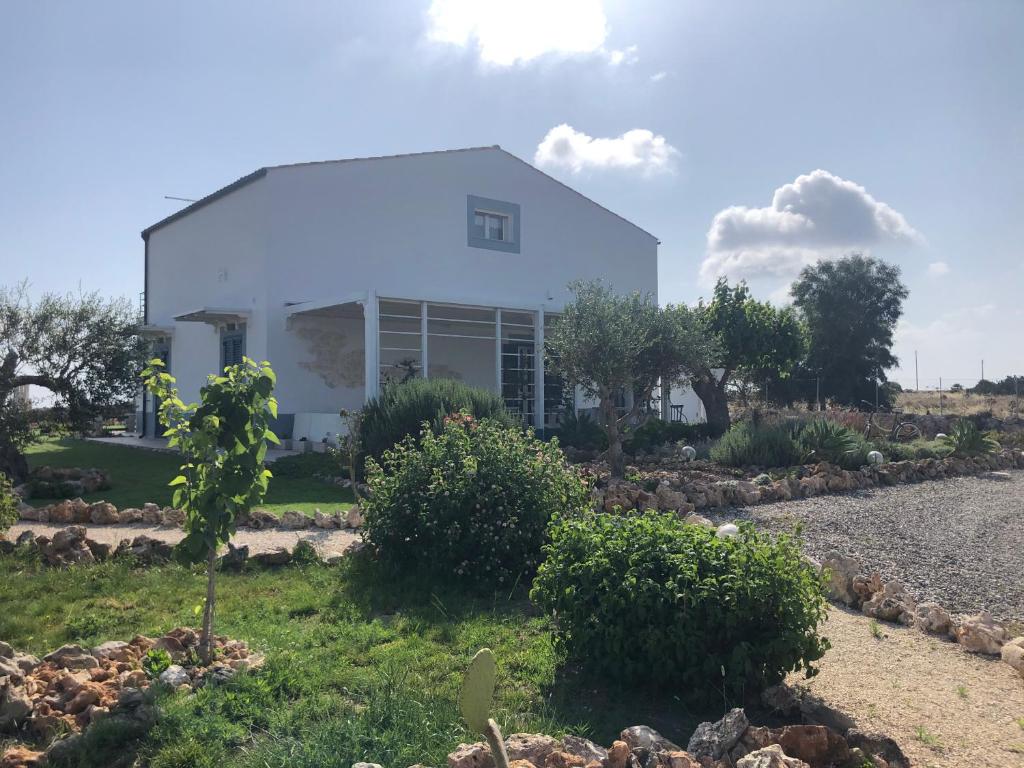 a white house with a garden in front of it at B&B Casa del Faro SanVallero Adults Only in Portopalo