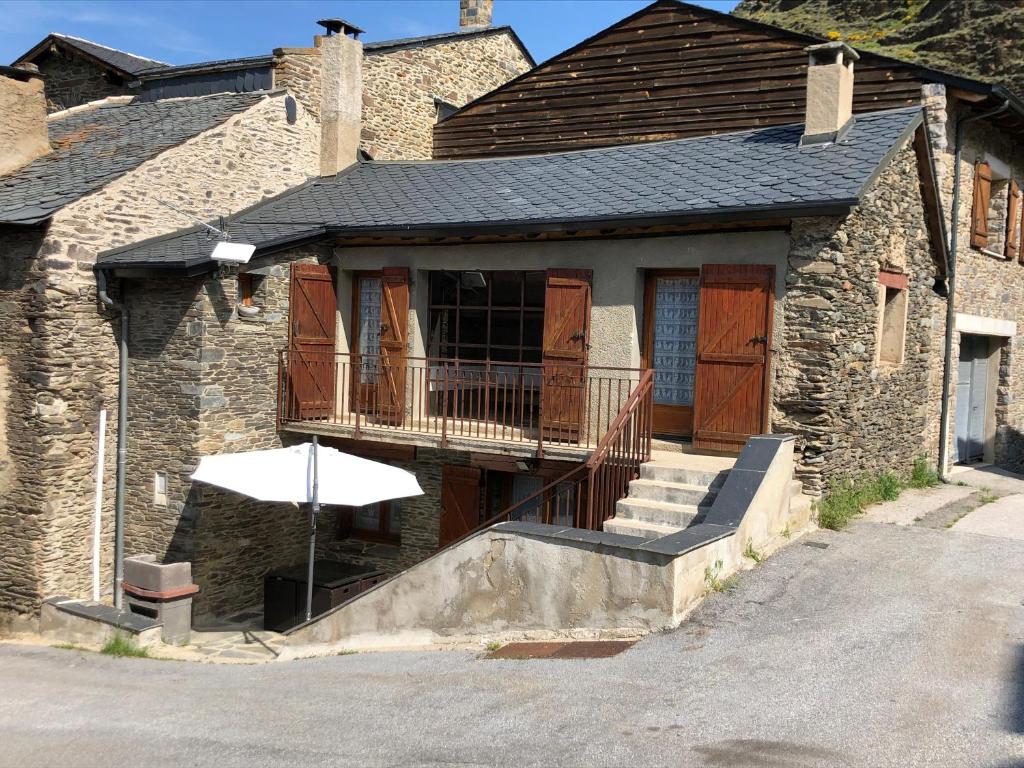 ein Steinhaus mit einem Balkon und einem Sonnenschirm in der Unterkunft Maison Olivotto in Valcebollère