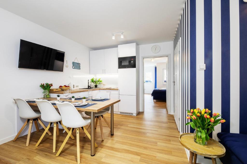 a kitchen and dining room with a table and chairs at Apartament 2B Blue Marine Poddąbie in Poddąbie