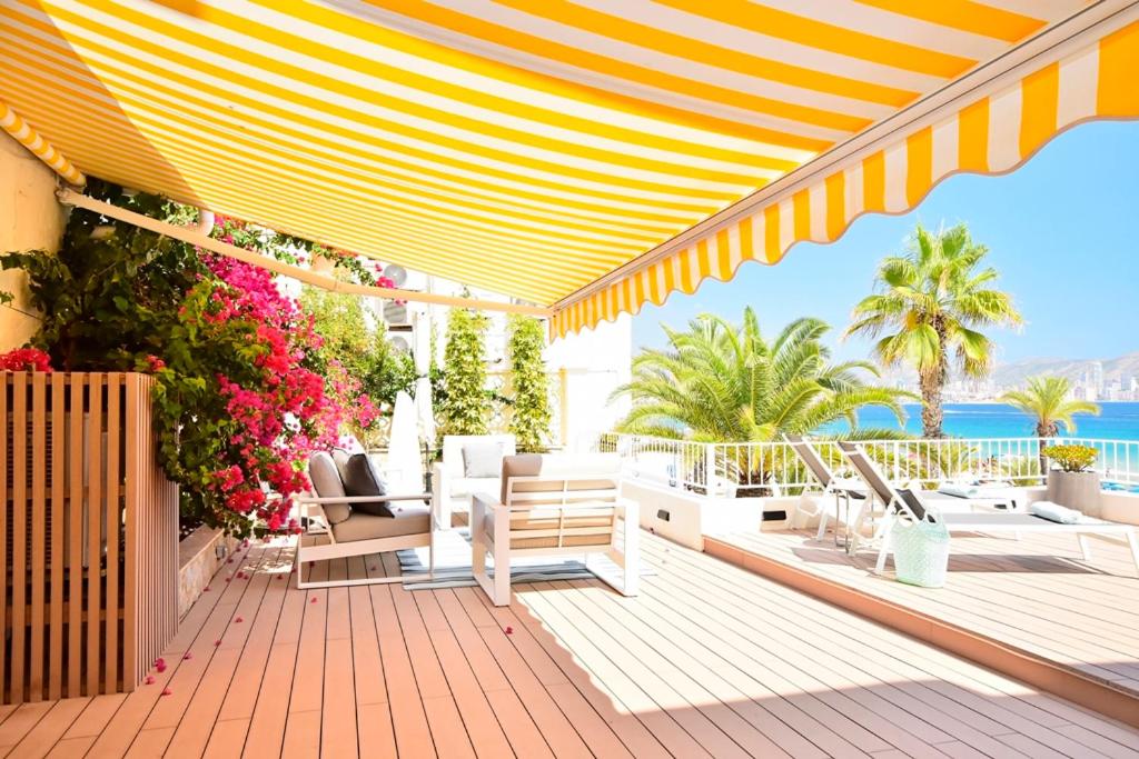 a patio with chairs and flowers on a deck at 70sqm private terrace in front of the sea & 107sqm brand new apartment in Benidorm