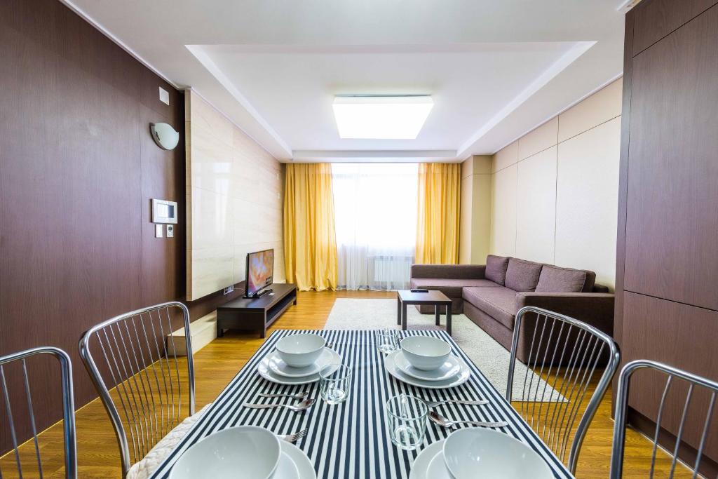 a living room with a table and chairs and a couch at THEADDRESS HIGHVILL Astana in Promyshlennyy