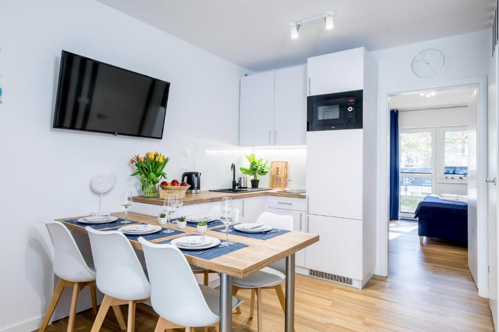 a kitchen and dining room with a table and chairs at Apartament 9B Blue Marine Poddąbie in Poddąbie