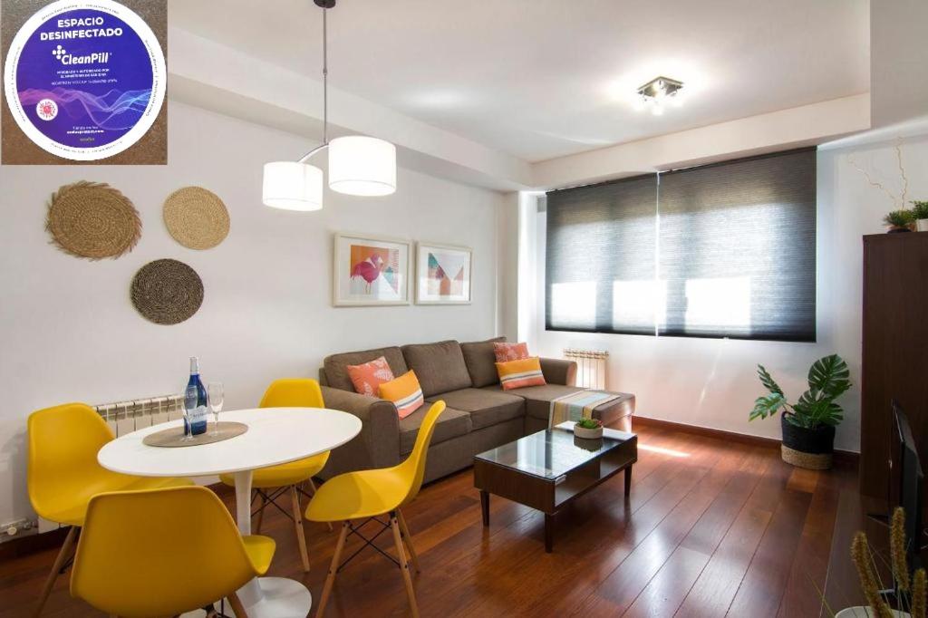 a living room with a couch and a table and yellow chairs at Apartamento Fórum-Ciencias con Piscina, Gym & Parking in Granada