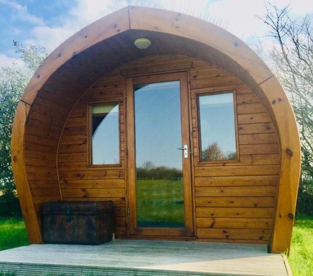 a small wooden cabin with a large door at The Oaks Glamping - Pips Cabin in Colkirk
