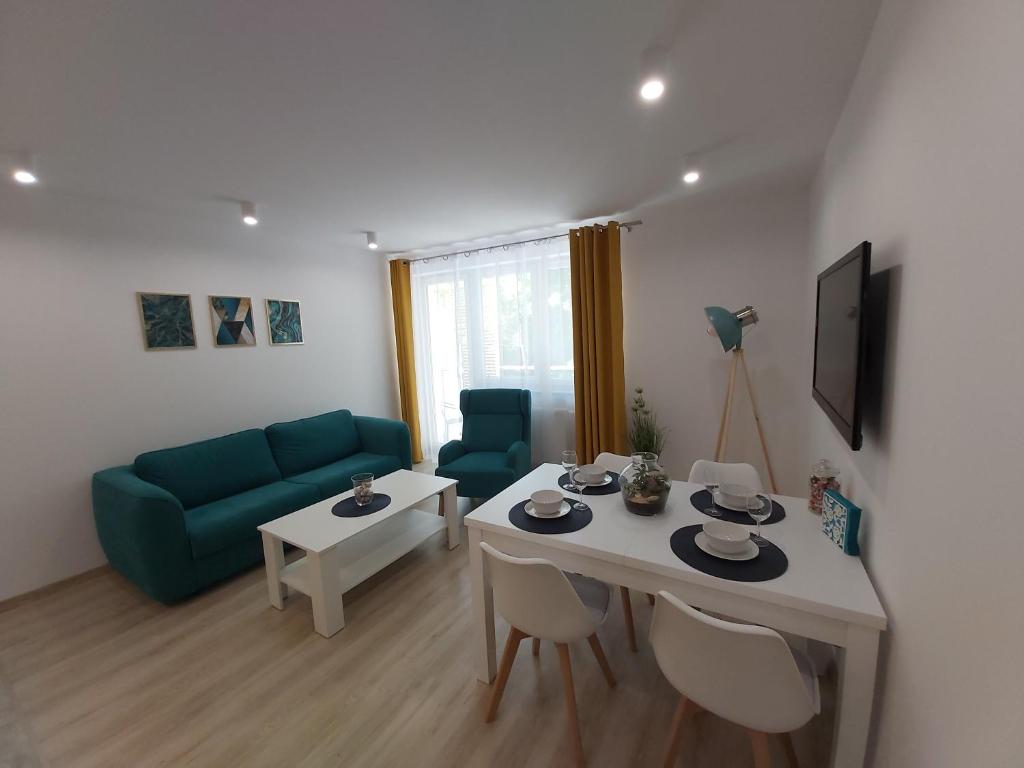 a living room with a table and a green couch at Apartament Przy Lesie Słoneczne Tarasy in Dziwnówek