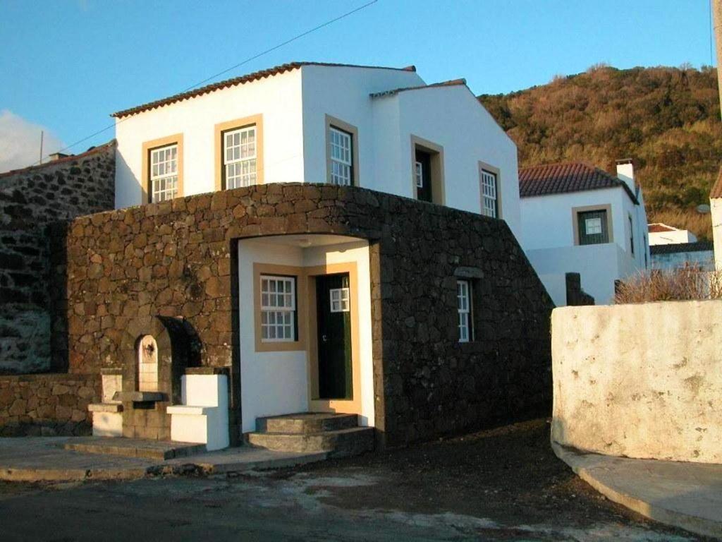 a white house with a stone wall next to it at One bedroom appartement with sea view terrace and wifi at Lajes Do Pico in Lajes do Pico