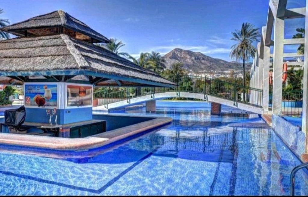 uma grande piscina com um gazebo ao lado de um edifício em Benalbeach Holidays Benalmâdena em Benalmádena