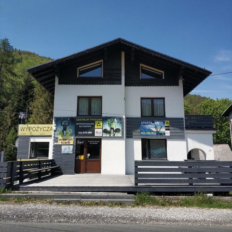 un edificio blanco y negro con un letrero. en Apartamenty Pod Gondolą, en Szczyrk