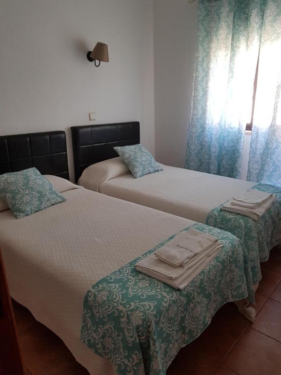 een slaapkamer met 2 bedden en handdoeken bij Quartos Abelha in Porto Covo