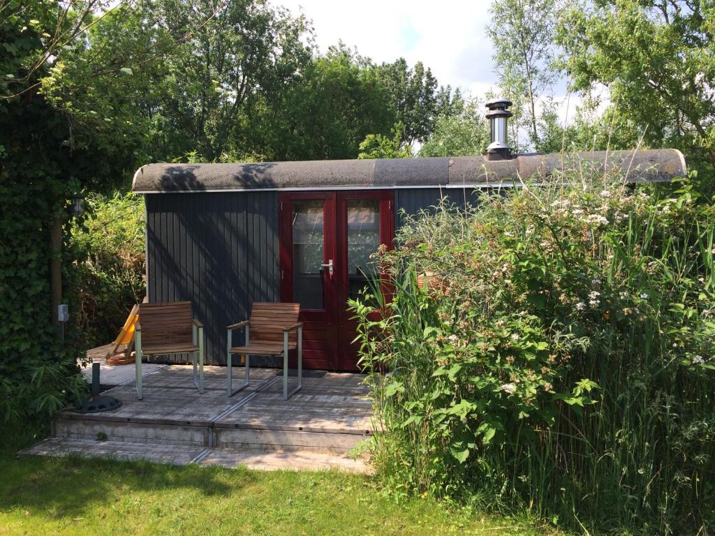 une petite maison avec 2 chaises sur une terrasse couverte dans l'établissement Gipsy wagon near Amsterdam and beach, à Velserbroek 