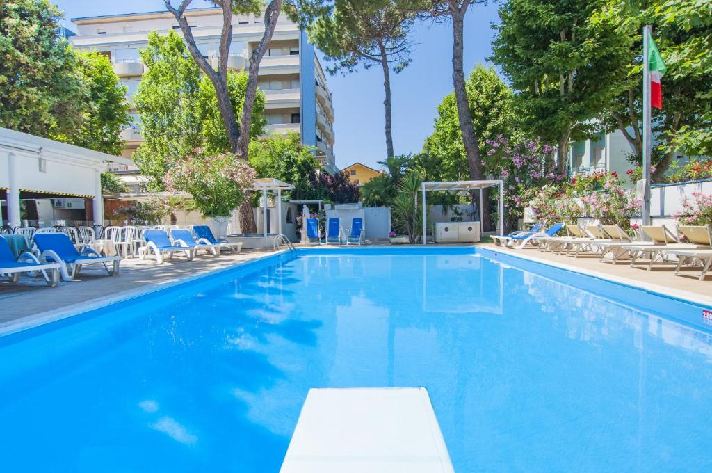 a large swimming pool with blue chairs and a building at Hotel Carillon in Bellaria-Igea Marina