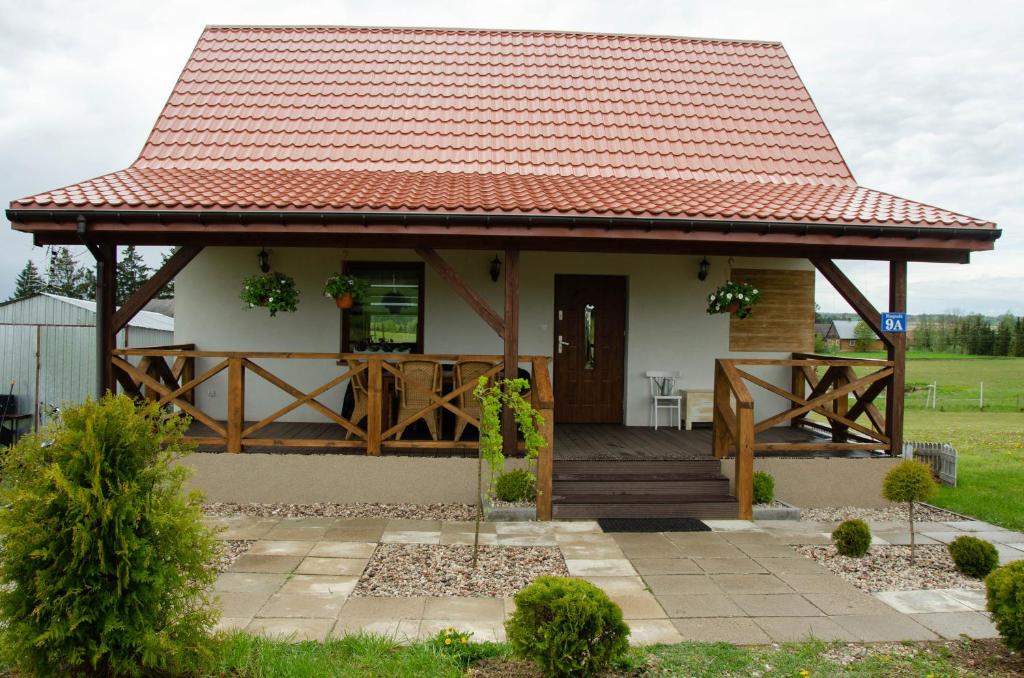 ein kleines Haus mit orangefarbenem Dach in der Unterkunft Domek Rospuda in Rospuda