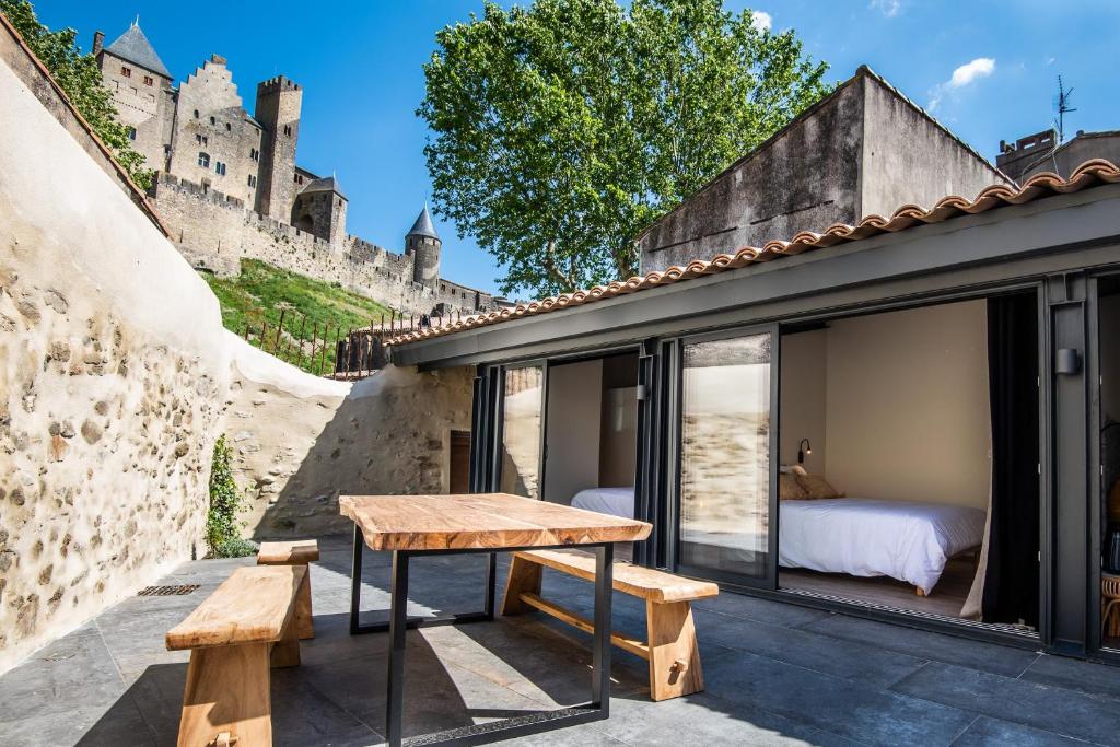 a room with a table and benches in front of a castle at Le Jardin de La Tour Pinte in Carcassonne