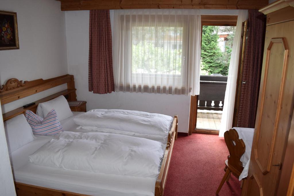 a bedroom with two white beds and a window at Bergsteiger-Zimmer Pension Obermair in Mayrhofen