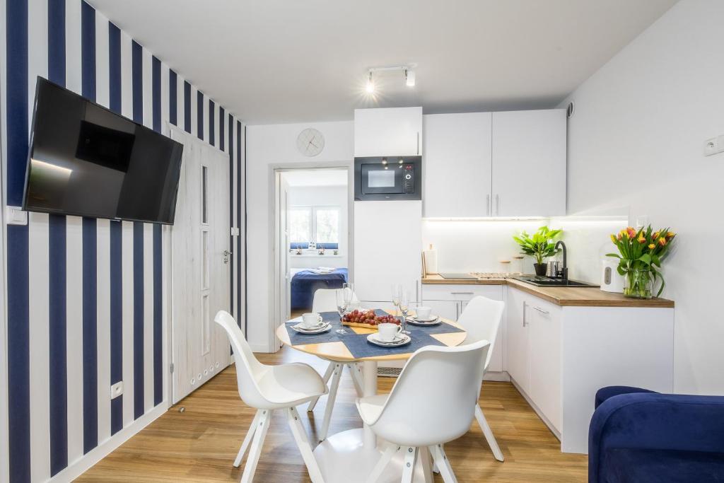 a kitchen and dining room with a table and chairs at Apartament 10B Blue Marine Poddąbie in Poddąbie