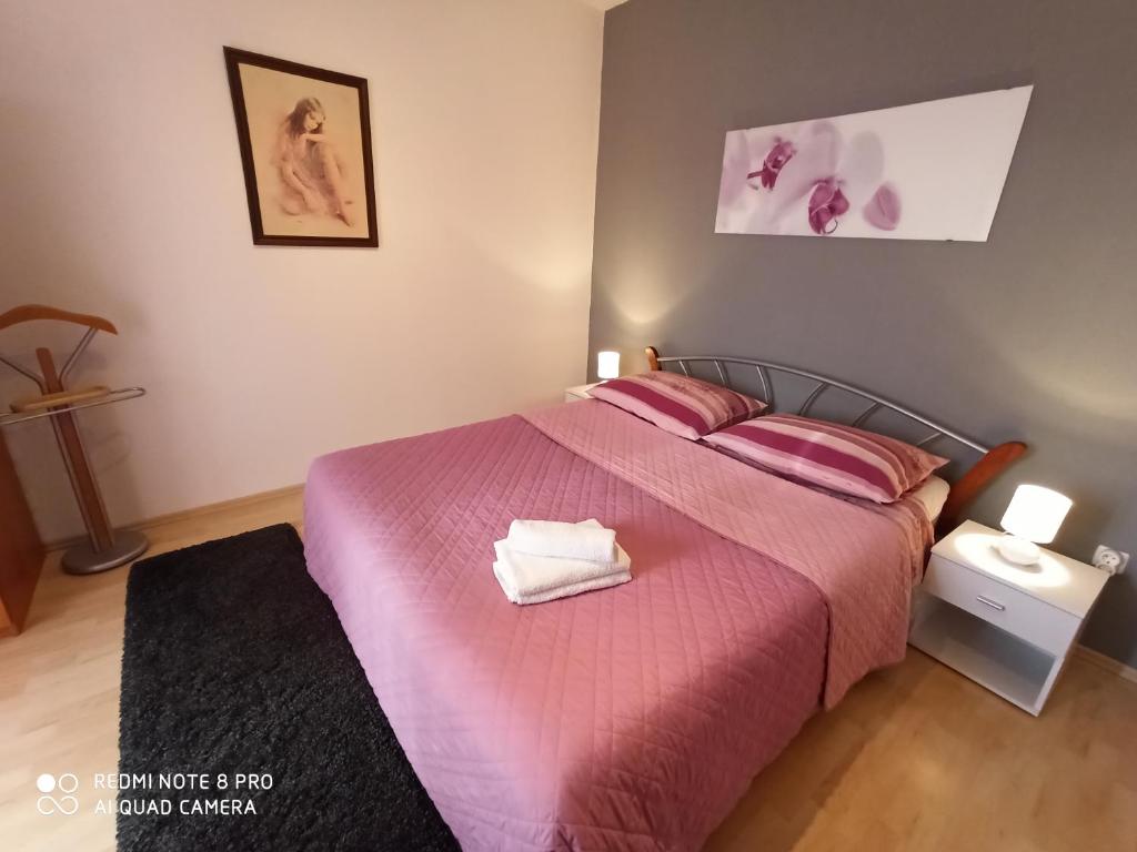 a bedroom with a bed with pink sheets and pillows at Apartments Roncevic in Zadar
