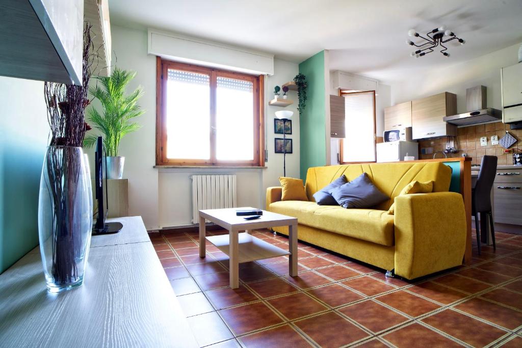 a living room with a yellow couch and a table at Casa Zoe Apartment Free parking,self check in & free wi fi in Parma