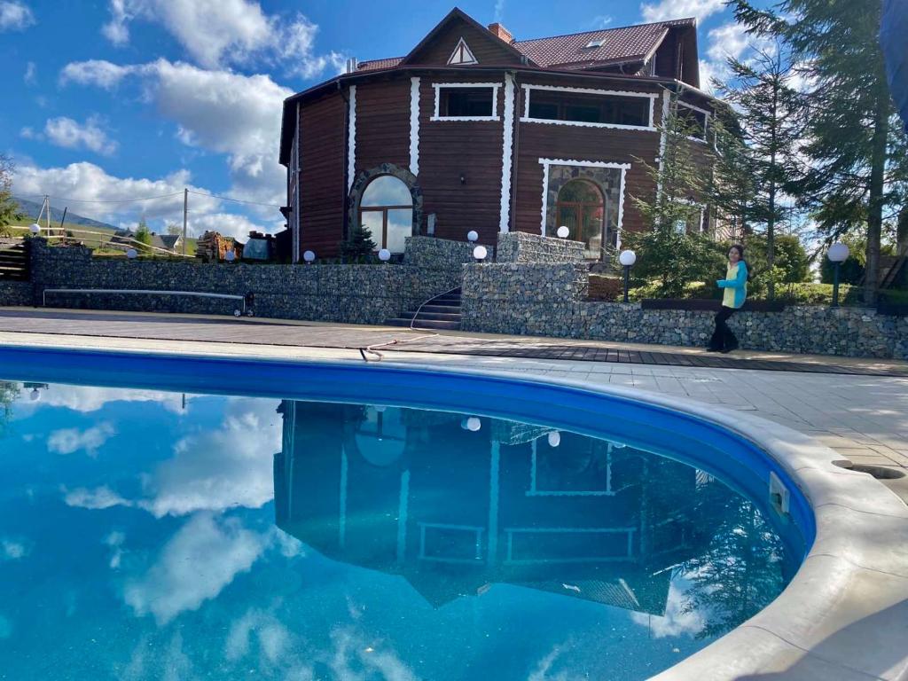 a house and a swimming pool in front of a house at Panorama Karpat in Yablunytsya