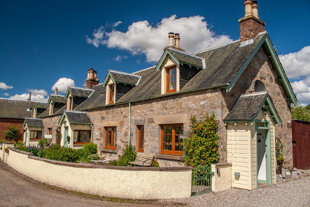 a large stone house with a black roof at Rosemount Bothy - Highland Cottage in Garve