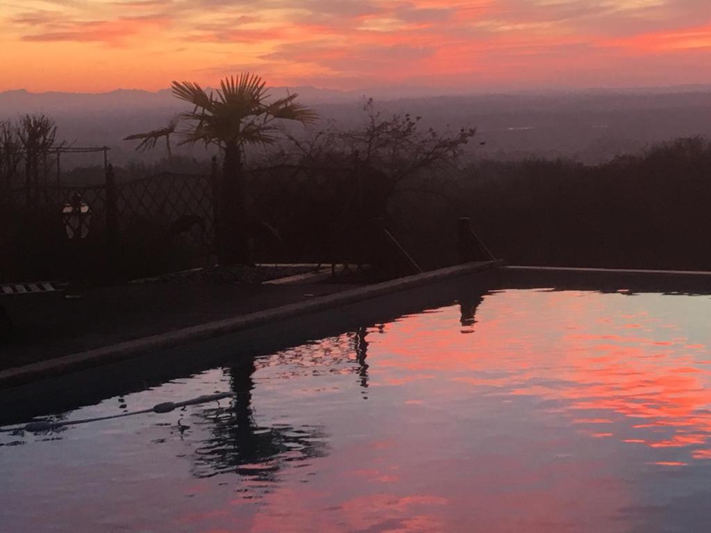 a swimming pool with a sunset in the background at Las Canéres in Castelnau-dʼArbieu