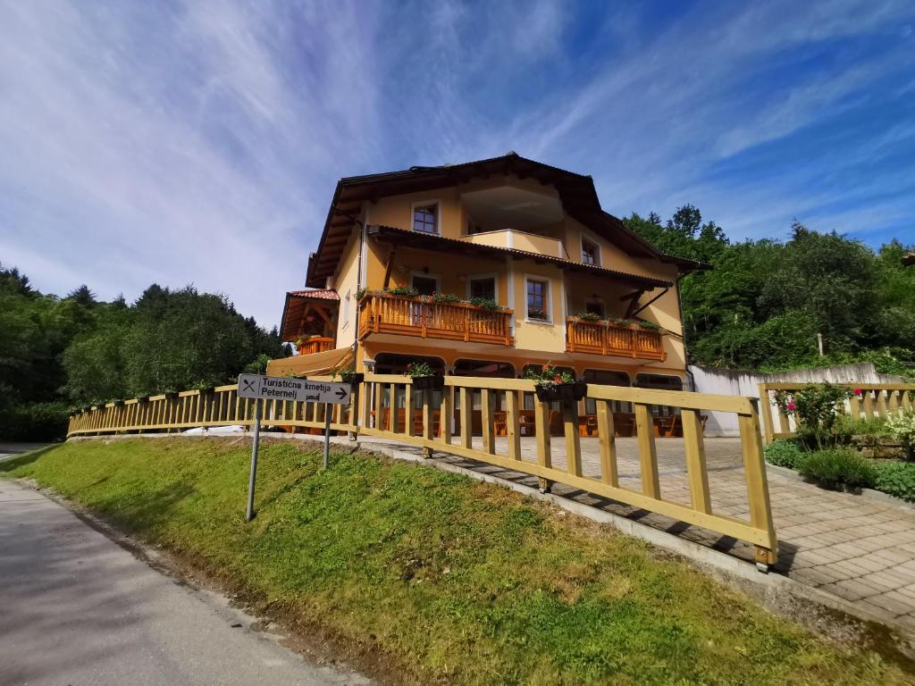 een huis met een houten hek voor een weg bij Farm Stay Peternelj in Ilirska Bistrica