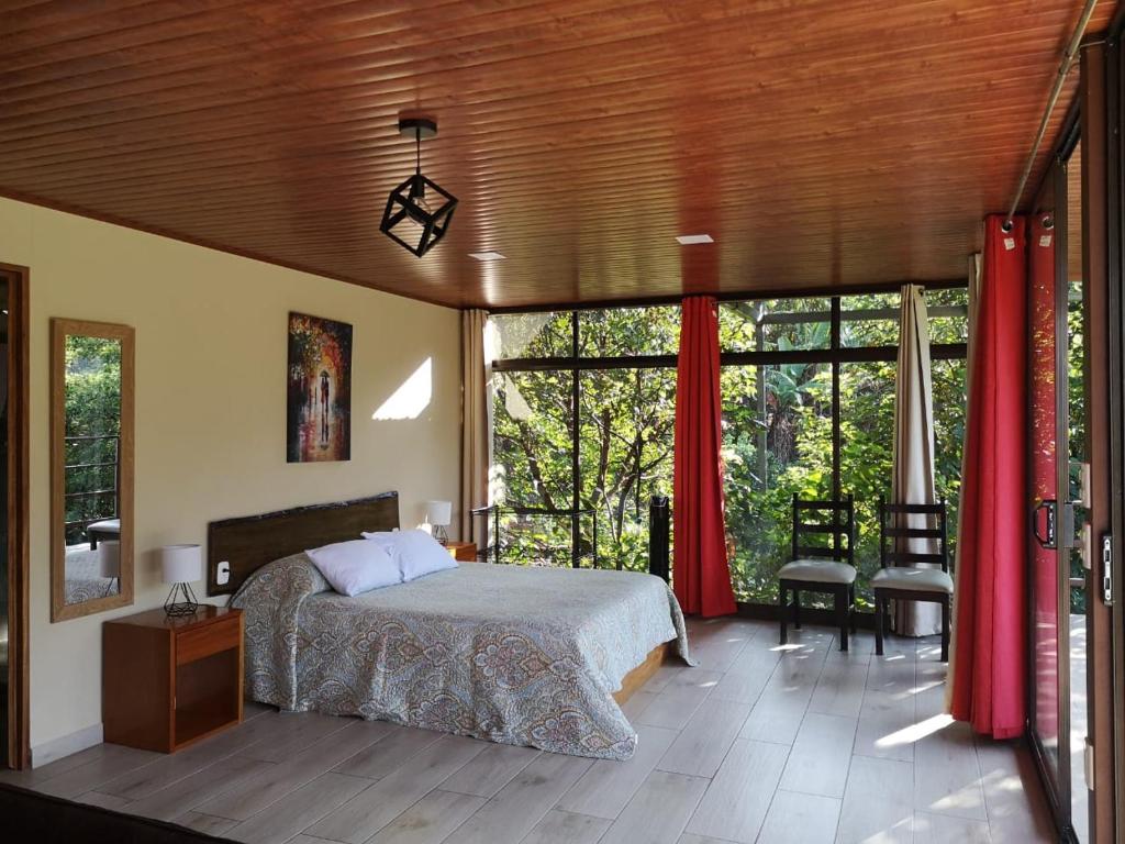 
a bedroom with a bed, chair, and a window at La Guayaba Monteverde in Monteverde Costa Rica
