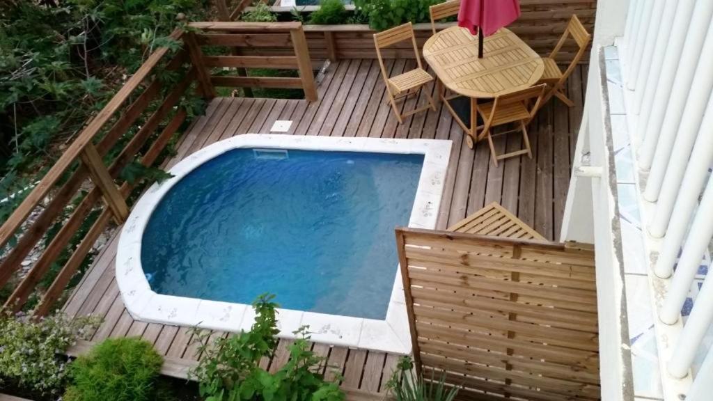 a deck with a swimming pool and a table and chairs at Maison d'une chambre avec piscine privee jacuzzi et jardin clos a Le Moule in Le Moule