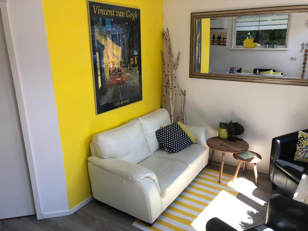een woonkamer met een witte bank en een gele muur bij Coastal Dreaming in Egmond aan Zee