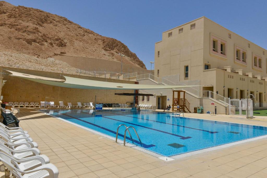 a large swimming pool with chairs and a building at HI - Massada Hostel in Ein Bokek