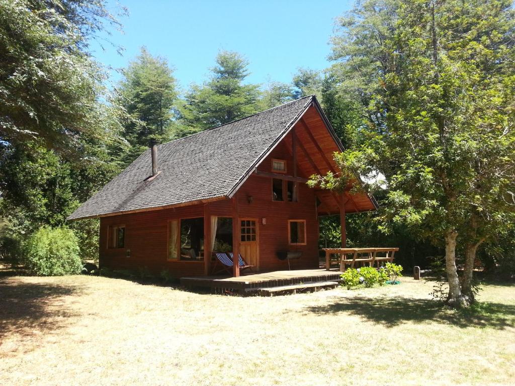 una pequeña casa de madera con porche y árboles en Cabañas Metreñehue - Parque Metreñehue, en Pucón