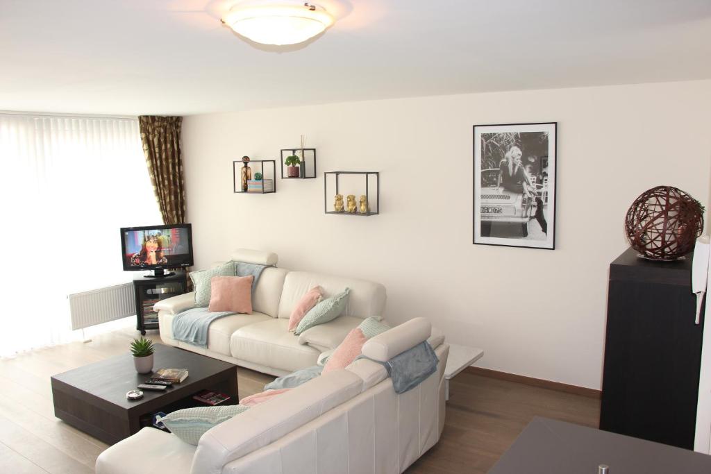 a living room with a white couch and a tv at Lichtrijk appartement Oostende in Ostend