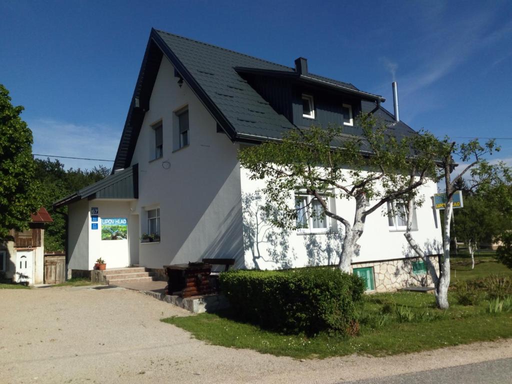 Biały dom z czarnym dachem w obiekcie Guest House Lipov Hlad w mieście Jeziora Plitwickie