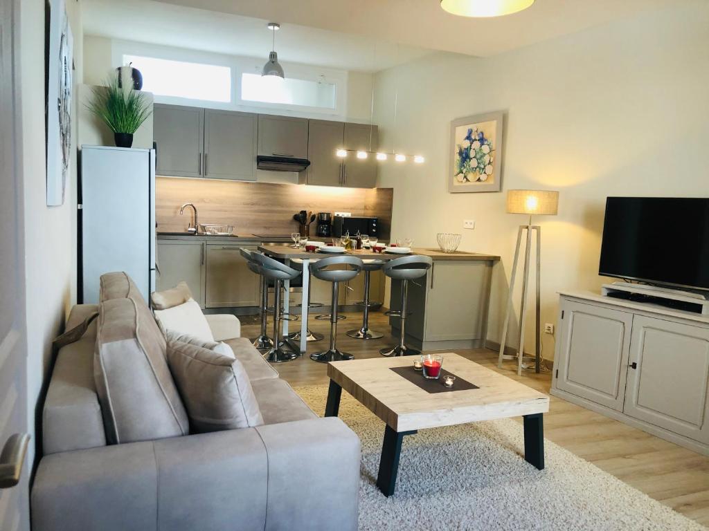 ein Wohnzimmer mit einem Sofa und einem Tisch sowie eine Küche in der Unterkunft Les volets rouges in Cavaillon