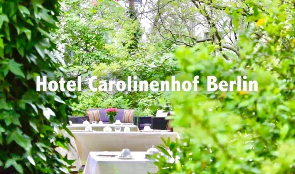 un grupo de mesas en un jardín con árboles en Hotel Carolinenhof, en Berlín