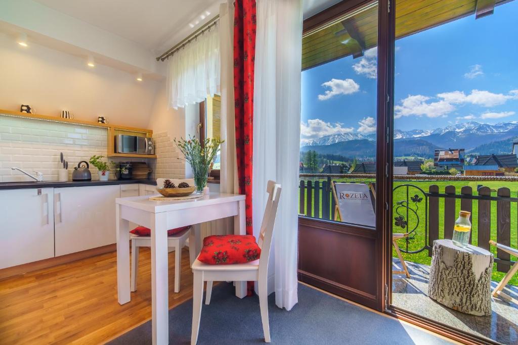 une cuisine et une salle à manger avec une table et un balcon dans l'établissement Apartamenty ROZETA - ZAKOPANE, à Zakopane