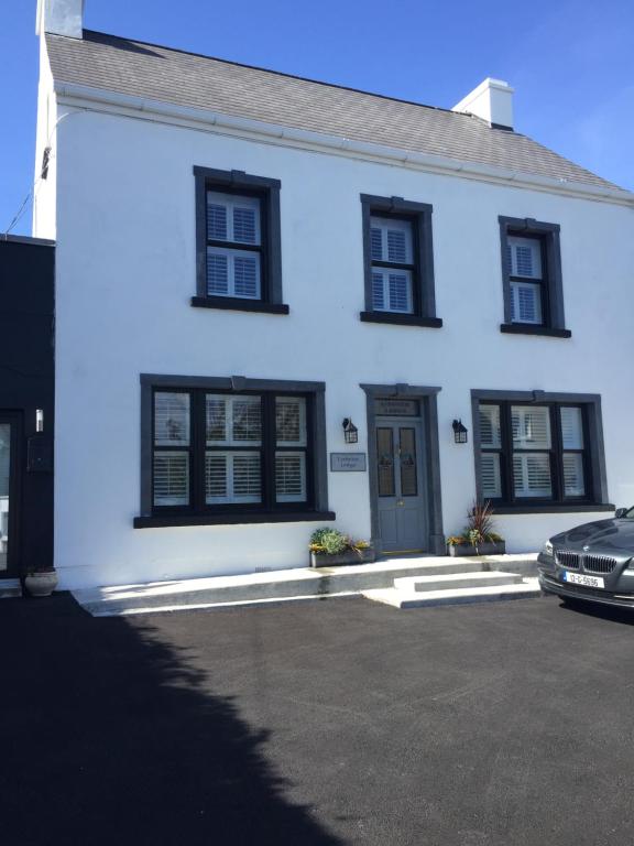 una casa blanca con ventanas negras y un coche en Lisheen Lodge, en Galway
