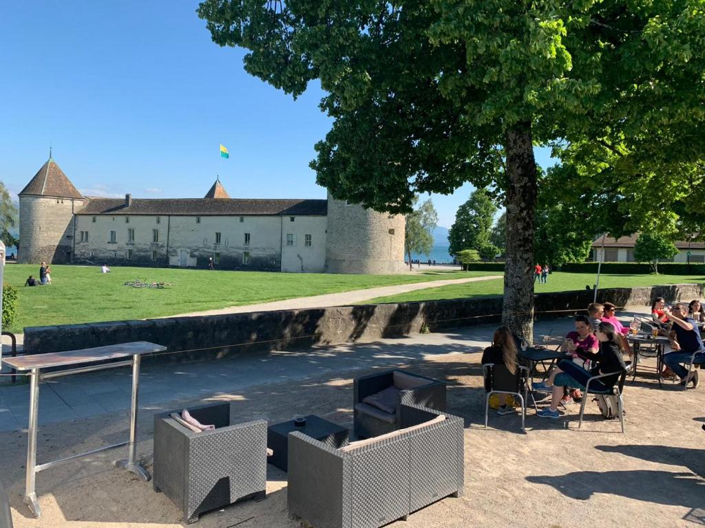 a group of people sitting in chairs under a tree at L'Hôtel by Hostellerie du Château in Rolle