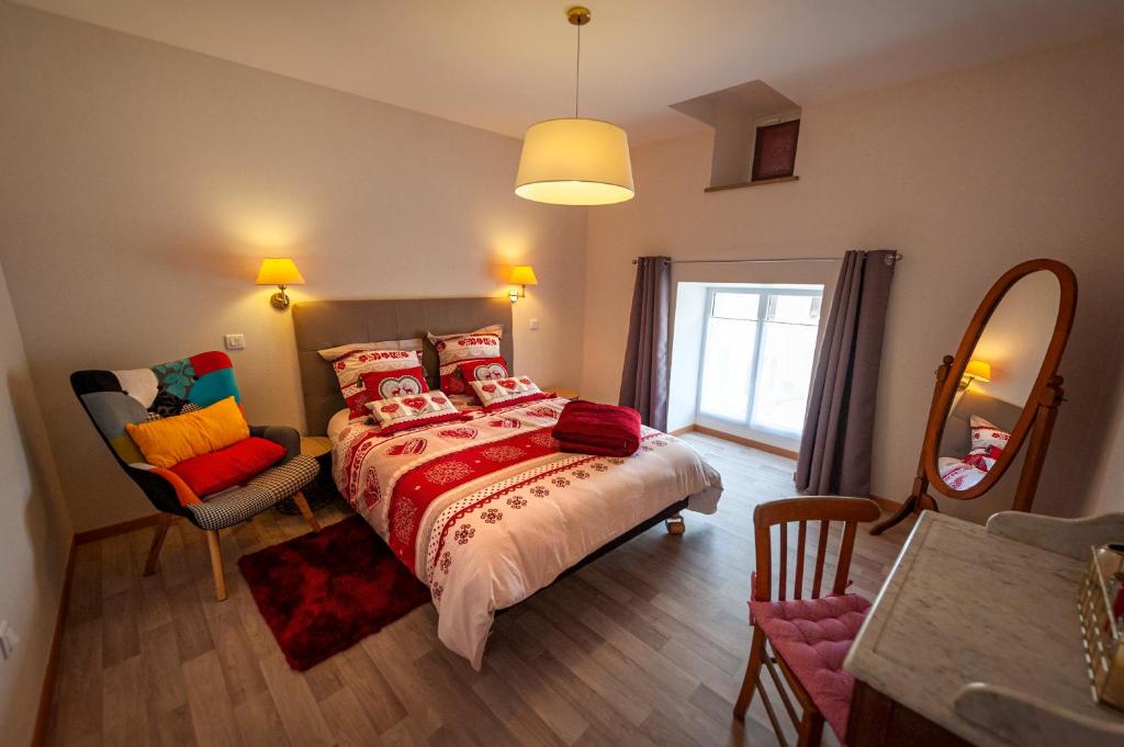 a bedroom with a bed with red pillows and a mirror at Chambres d hôtes LA FERME DES BOUTONS in Frizon-la-Haute