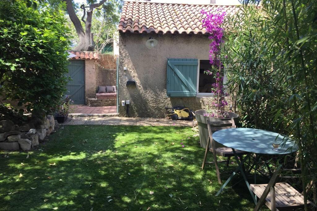 - une table et des chaises dans une cour avec une maison dans l'établissement LA CASSIRENE - Maisonnette centre Cassis - Jardin, à Cassis