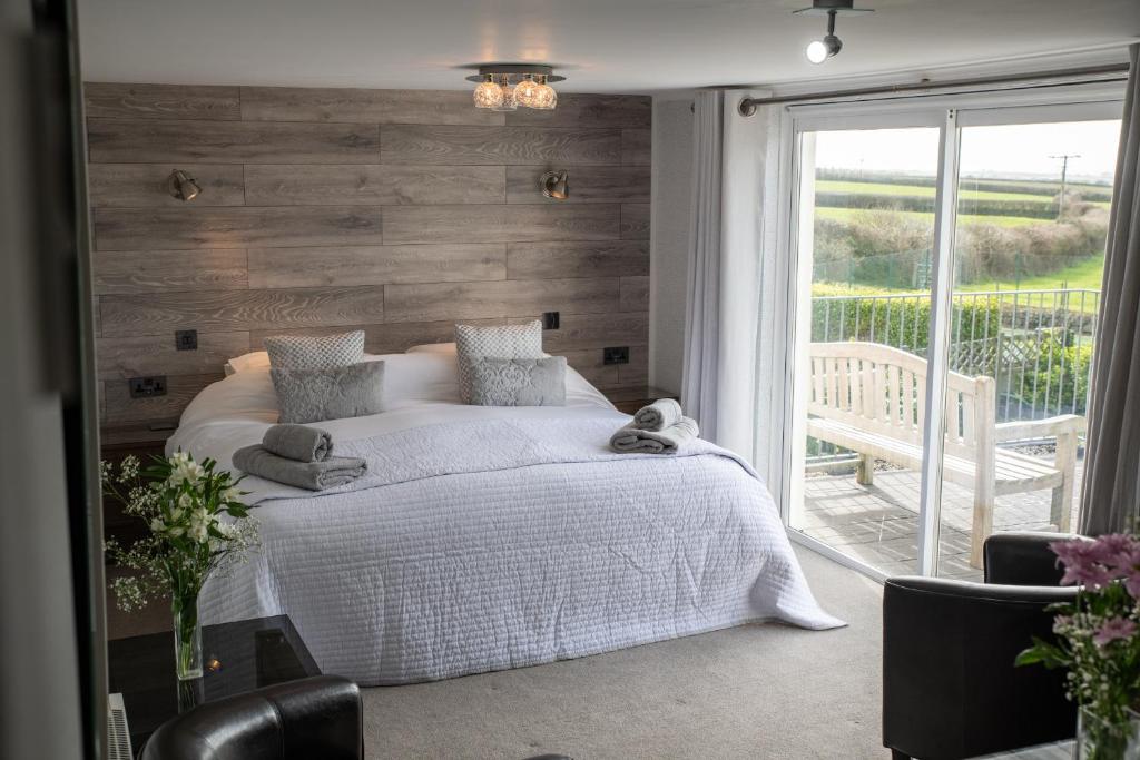 a bedroom with a white bed and a large window at Tregaddra Farm B&B in Helston