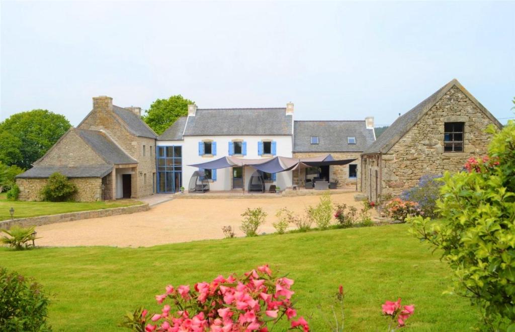 una casa grande con un patio con flores rosas en Maison de 6 chambres avec jacuzzi jardin amenage et wifi a Plougonven, en Plougonven